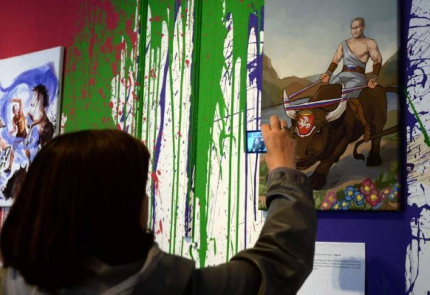 Una mujer observa uno de los cuadros pintados en honor a Putin, en la exposición artística realizada en Moscú.