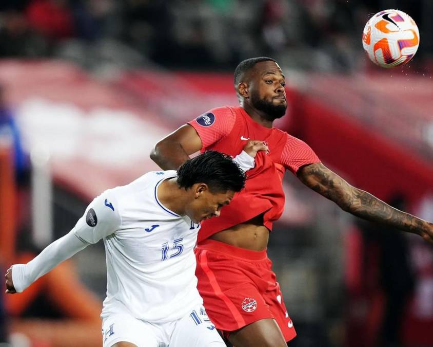 Denil Maldonado saltando por el balón con el goleador canadiense Cyle Larin.