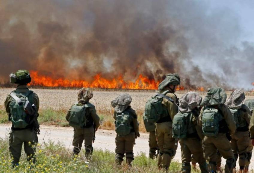 Soldados Israelíes observan mientras el fuego arrasa con un campo en la Franja de Gaza.
