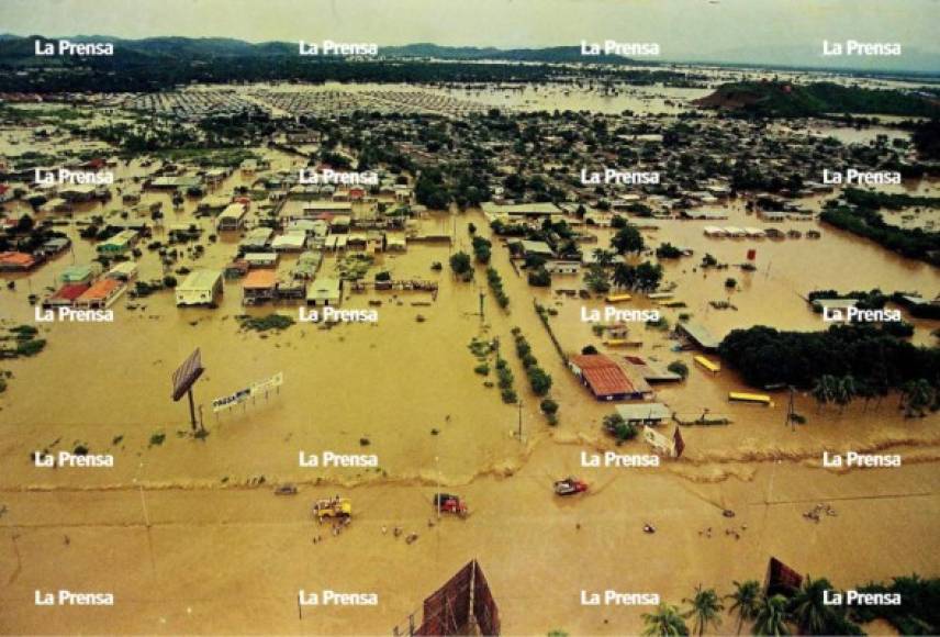 Entrada a la colonia La Planeta durante. La carretera hacia La Lima y el bulevar de la entrada a La Planeta estuvieron anegados varios días con las aguas del Mitch. Después. Las vías públicas permanecen igual que hace 20 años.