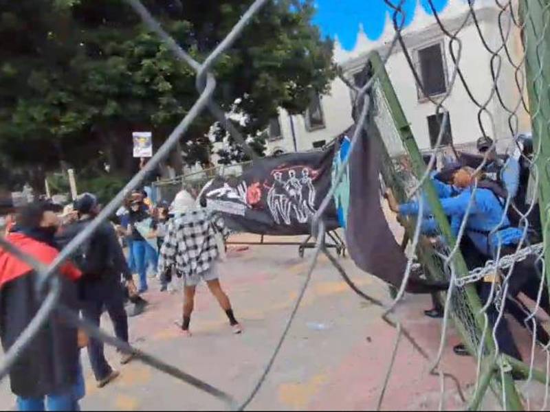 Agentes de la Policía Nacional forman una barrera para evitar que los estudiantes derriben la valla de seguridad instalada en los bajos del Congreso Nacional.