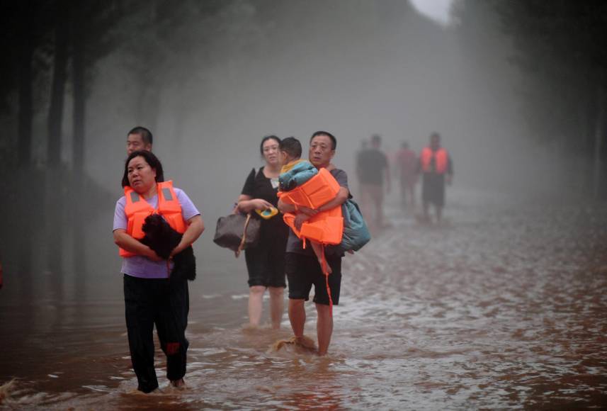 Esta foto tomada el 1 de agosto de 2023 muestra a personas evacuando un área inundada después de fuertes lluvias en Zhuozhou, ciudad de Baoding, en la provincia norteña de Hebei, China. 