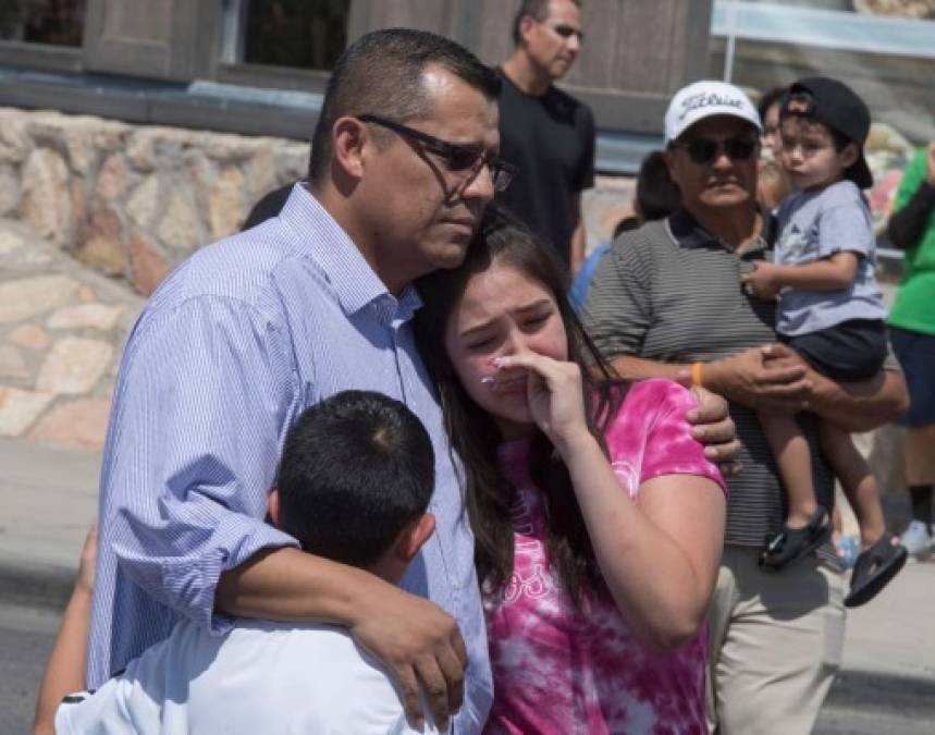 Members of the Medina family react beside a makeshift memorial outside the Cielo Vista Mall Wal-Mart (background) where a shooting left 20 people dead in El Paso, Texas, on August 4, 2019. - Texas authorities are investigating the Saturday mass shooting at a Walmart store in El Paso as a possible hate crime, the city's police chief said, as authorities study an online manifesto linked to the suspect. A 21-year-old from Allen, a suburb of Dallas, surrendered to police outside the store after the rampage that left 20 people dead and 26 wounded.US media identified him as Patrick Crusius, who is white, and linked him to a 'manifesto' posted online that includes passages railing against the 'Hispanic invasion' of Texas. (Photo by Mark RALSTON / AFP)