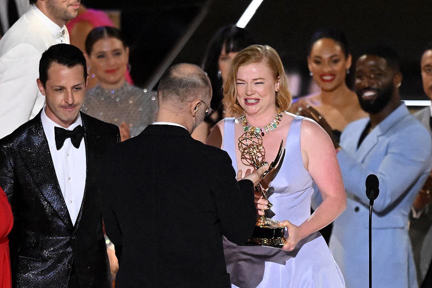 El guionista británico Jesse Armstrong (C) entrega el Emmy a la actriz australiana Sarah Snook después de aceptar el premio a la Serie Dramática Sobresaliente por “Succession” junto con el elenco y el equipo.