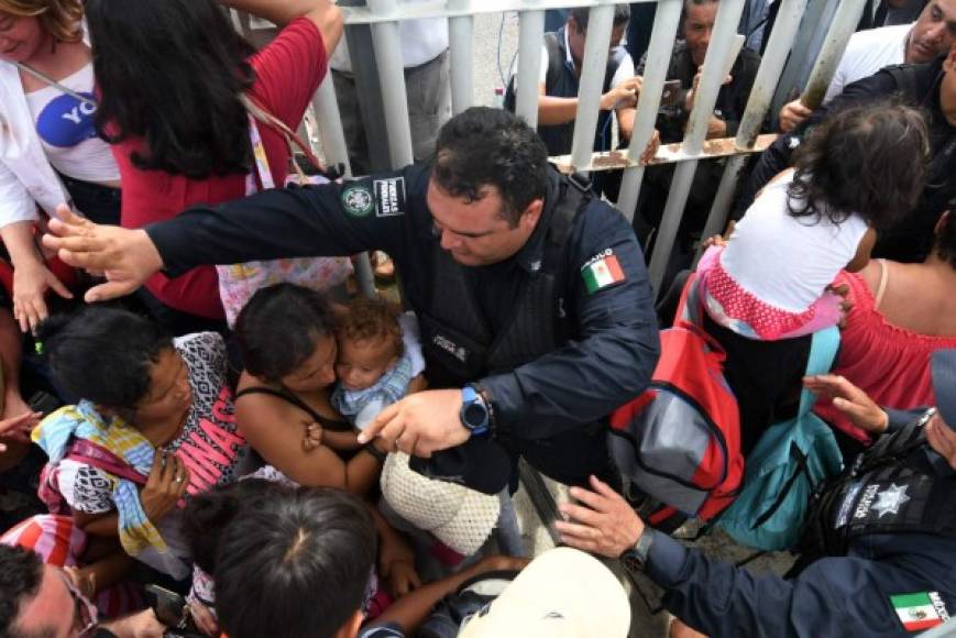 Un agente mexicano ayuda a una madre con su hijo en el paso fronterizo.