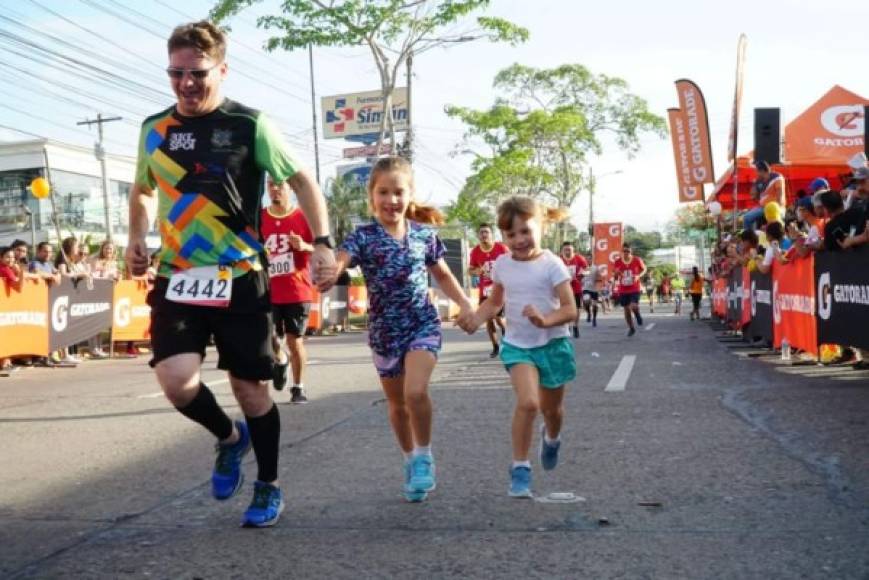 Un padre de familia haciendo cadena humana con sus pequeñas durante el recorrido de la Maratón.