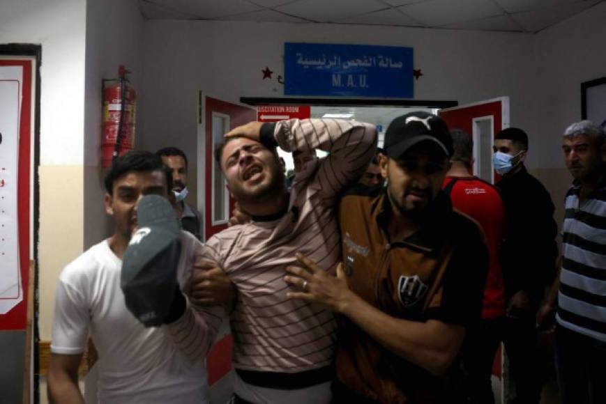 TOPSHOT - Palestinians react at a hospital in the northern Gaza Strip amid a flare-up of Israeli-Palestinian violence, on May 10, 2021. - Nine people were killed amid air raids in the Gaza Strip, local authorities said, but it was not clear whether the fatalities were caused by Israeli strikes. Israel has confirmed it was bombing Hamas targets in Gaza in response to earlier rocket fire directed towards Israel. (Photo by MOHAMMED ABED / AFP)