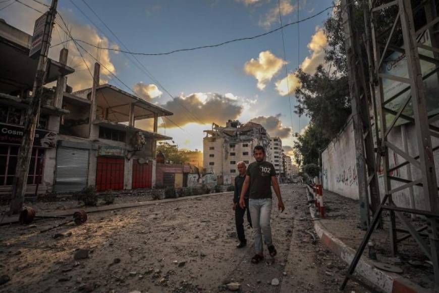Dos personas caminan junto a un edificio destruido después de un ataque aéreo israelí en la ciudad de Gaza, el 17 de mayo de 2021. Foto: EFE / EPA / HAITHAM IMAD
