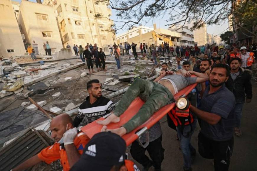 Palestinos sacan a uno de los sobrevivientes de debajo de los escombros de un edificio, después de que fuera golpeado por los ataques israelíes, en la ciudad de Gaza, el 16 de mayo de 2021. (Foto de MOHAMMED ABED / AFP)