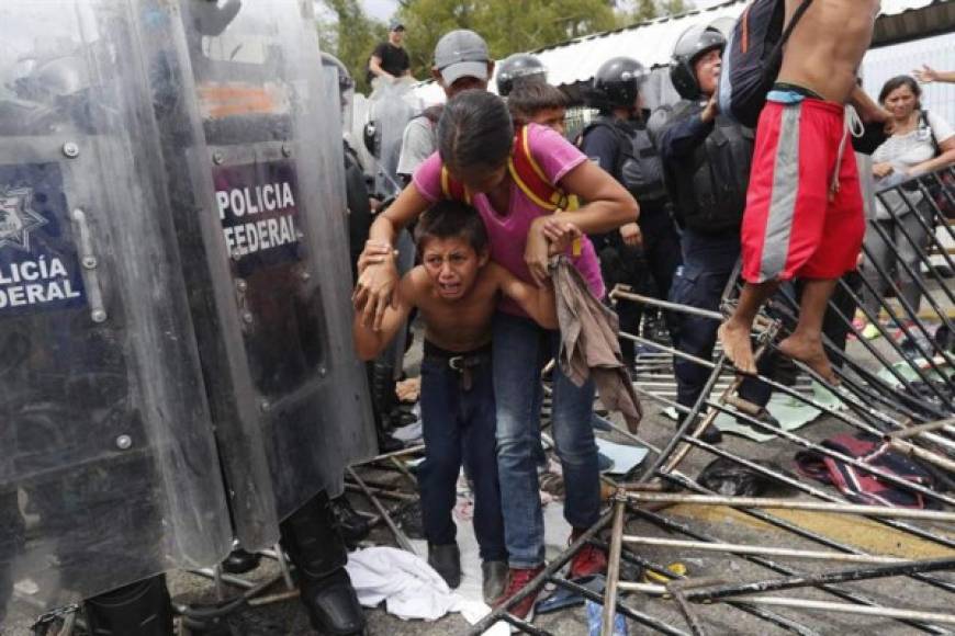 La angustia se apodera de esta madre y su hijo que caminan entre los detrozos de un paso fronterizo y los escudos de los agentes federales mexicanos.