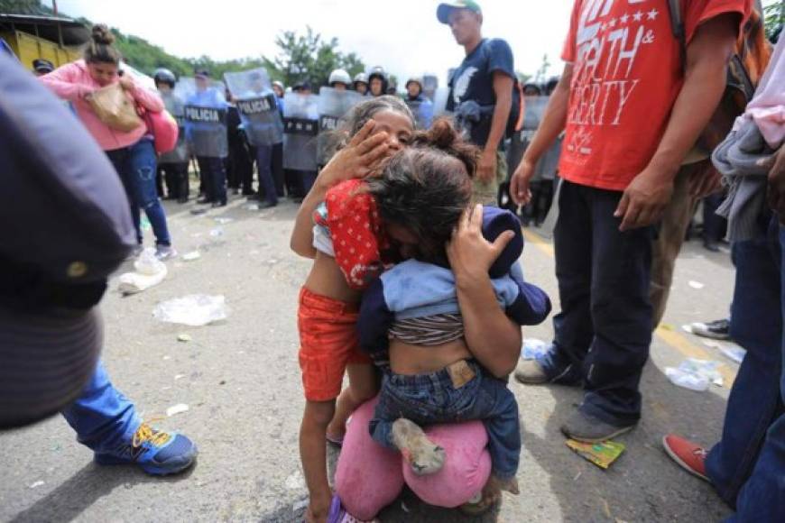 National Police riot police officers observe Honduran migrants moving to Agua Caliente, on the border between Honduras and Guatemala, on their way to the United States, on January 15, 2021. - Hundreds of asylum seekers are forming new migrant caravans in Honduras, planning to walk thousands of kilometers through Central America to the United States via Guatemala and Mexico, in search of a better life under the new administration of President-elect Joe Biden. (Photo by Orlando SIERRA / AFP)