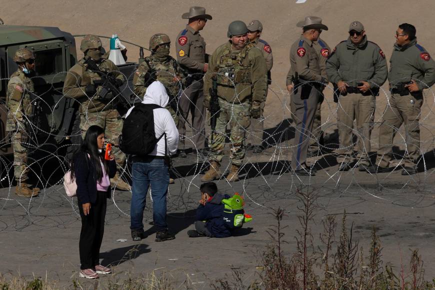 Migrants seeking asylum in the United States ask Texas National Guard agents to let them turn themselves in with Border Patrol agents in the El Paso, Texas, US. border with Ciudad Juarez, Chihuahua state, Mexico, on December 20, 2022. - Title 42, a President Donald Trump pandemic-era law that authorize United States border officials to expel migrants is supposed to end on December 21. (Photo by Herika Martinez / AFP)
