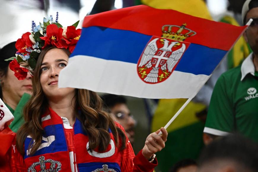 Una aficionada de Serbia portando la bandera de su país y un colorido arreglo de flores en su cabeza.