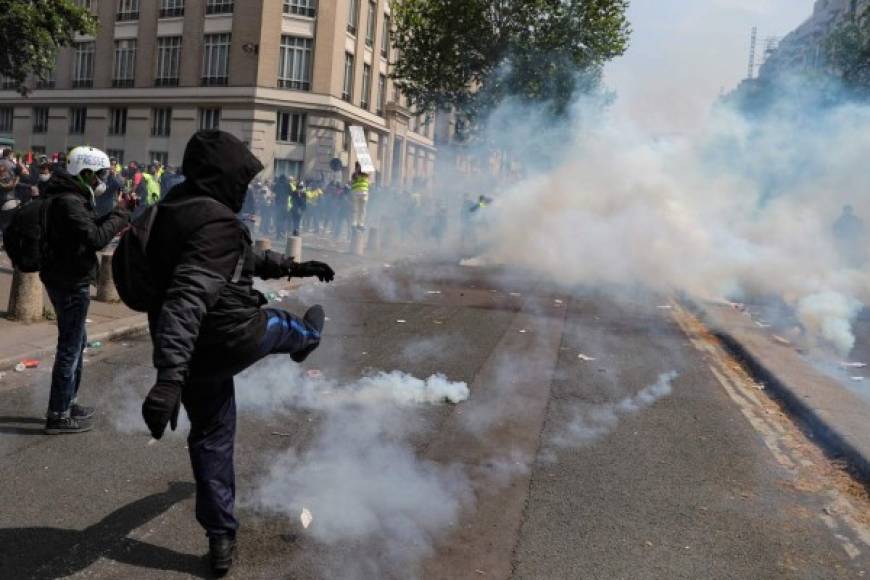 Protesters taking part in an event called 'BenallApero', on May 1, 2019, prevent police from accessing the Contrescarpe square in Paris, a site where a former Elysee senior security officer had been caught on video hitting a protester during a May Day rally. - The 'BenallApero' refers to last year's scandal triggered by a video showing Alexandre Benalla, a French president's former bodyguard, roughing up protesters during a May Day rally. (Photo by Anne-Christine POUJOULAT / AFP)