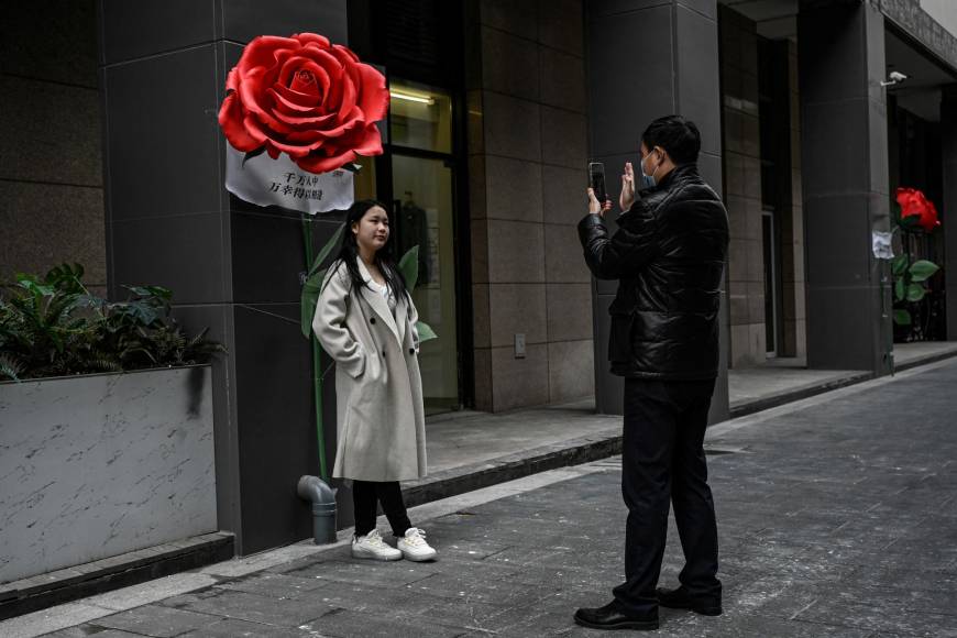 Una pareja se toma fotos frente a unas decoraciones en un centro comercial de Beijing, China, que este año celebra su primer San Valentín sin restricciones anticovid.