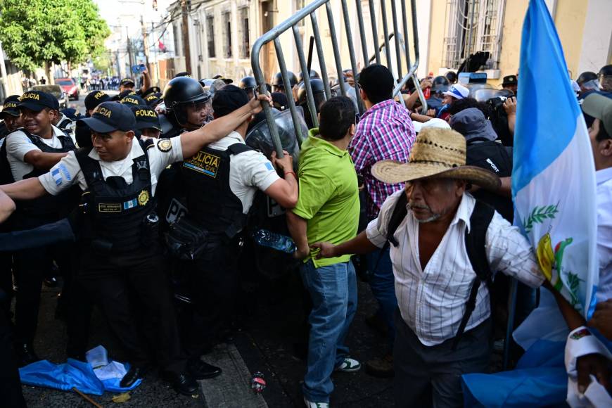 Un tercer anillo de seguridad con agentes antidisturbios y policías militares frenó el avance de la multitud, que hace sonar trompetas de plástico y ondea banderas de <b>Guatemala</b>, aunque hasta el momento la policía no ha utilizado la fuerza para dispersarlos ni gases lacrimógenos.
