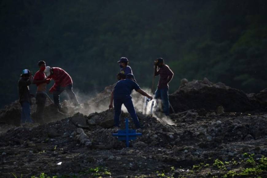 Un hombre pinta una cruz, mientras otros trabajan abriendo fosas para sepultar personas en el cementerio Los Ángeles, al norte de la capital hondureña, Tegucigalpa.