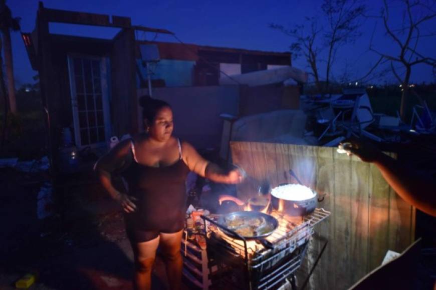 Maria prepares food during nightfall next to her home, destroyed by Hurricane Maria, in Toa Alta, Puerto Rico, on September 25, 2017.<br/>The US island territory, working without electricity, is struggling to dig out and clean up from its disastrous brush with the hurricane, blamed for at least 33 deaths across the Caribbean. / AFP PHOTO / HECTOR RETAMAL