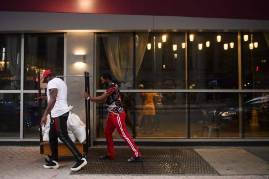 People push sandbags on a hotel luggage cart in New Orleans, Louisiana on August 28, 2021 before the arrival of Hurricane Ida. - Owners were boarding up their shops and evacuations were underway on August 28, 2021 as Hurricane Ida was on a path to hit New Orleans 16 years to the day the southern US city was devastated by Hurricane Katrina. (Photo by Patrick T. FALLON / AFP)