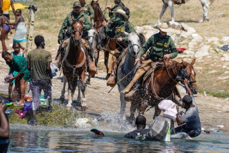 United States Border Patrol agents on horseback tries to stop Haitian migrants from entering an encampment on the banks of the Rio Grande near the Acuna Del Rio International Bridge in Del Rio, Texas on September 19, 2021. - The United States said Saturday it would ramp up deportation flights for thousands of migrants who flooded into the Texas border city of Del Rio, as authorities scramble to alleviate a burgeoning crisis for President Joe Biden's administration. (Photo by PAUL RATJE / AFP)