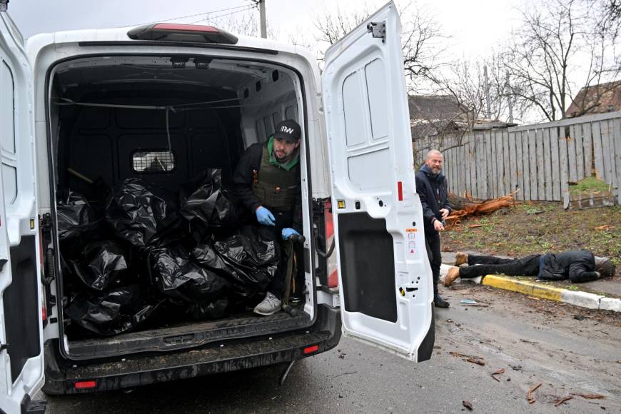 A communal worker standing inside a van loaded with body bags, waits for another body to be wrapped and collected by a colleague inthe town of Bucha, not far from the Ukrainian capital of Kyiv on April 3, 2022. - Britain, France, Germany, the US and NATO all voiced horror at Ukrainian reports on April 2, 2022, of nearly 300 bodies lying in the street in Bucha, with some appearing to have been bound by their hands and feet before being shot. (Photo by Sergei SUPINSKY / AFP)