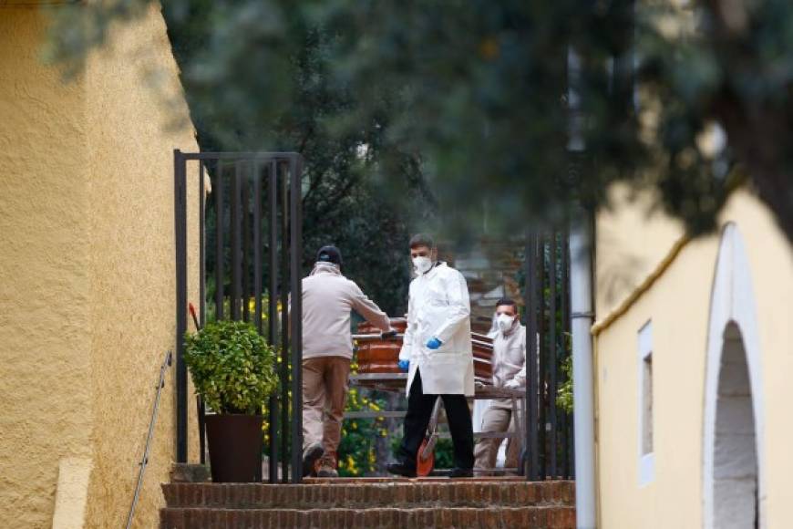Trabajadores de una morgue en España trasladan muertos por coronavirus en ataúdes.