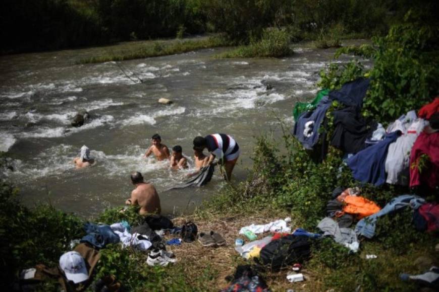 Honduran migrants taking part in a caravan heading to the US, take a bath and wash their clothes in the Huixtla river, in Huixtla, Chiapas state, Mexico, on October 23, 2018. - Thousands of mainly Honduran migrants heading to the United States -- a caravan President Donald Trump has called an 'assault on our country' -- stopped to rest Tuesday after walking for two days into Mexican territory. (Photo by Pedro PARDO / AFP)