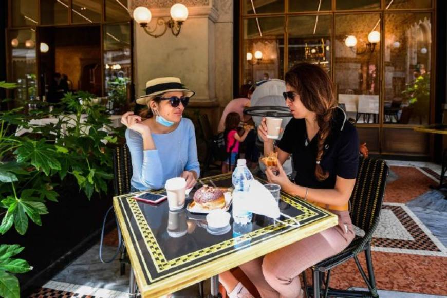Women have coffee and pastry at Cafe Cracco in Milan on May 18, 2020 during the country's lockdown aimed at curbing the spread of the COVID-19 infection, caused by the novel coronavirus. - Restaurants and churches reopen in Italy on May 18, 2020 as part of a fresh wave of lockdown easing in Europe and the country's latest step in a cautious, gradual return to normality, allowing businesses and churches to reopen after a two-month lockdown. (Photo by Miguel MEDINA / AFP)