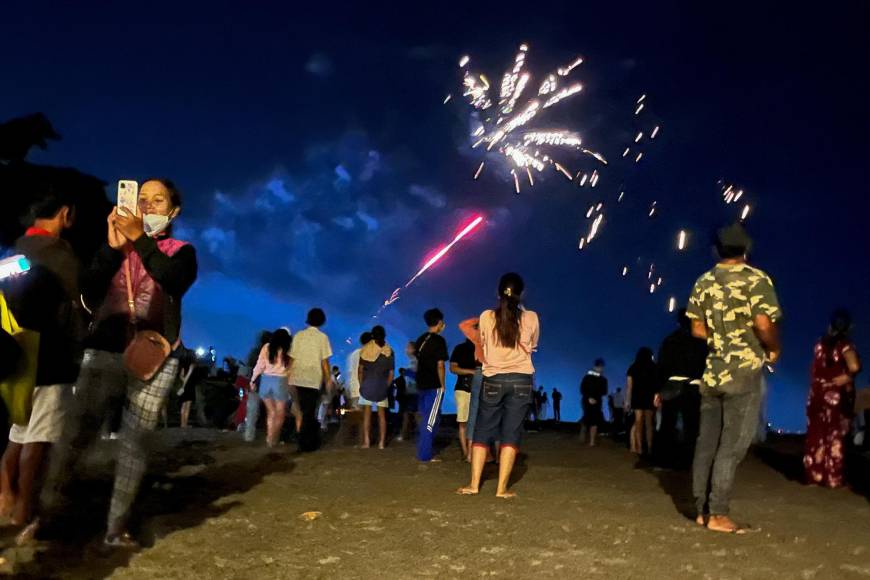 La gente ve los fuegos artificiales que parten desde la playa para recibir el año nuevo el 1 de enero de 2022 en Bali, Indonesia. 