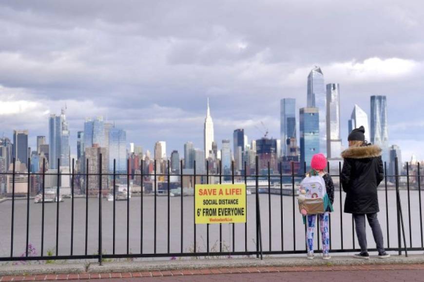 Una mujer y una niña miran la vista de Manhattan, de pie junto a una de las muchas señales de distancia social . AFP