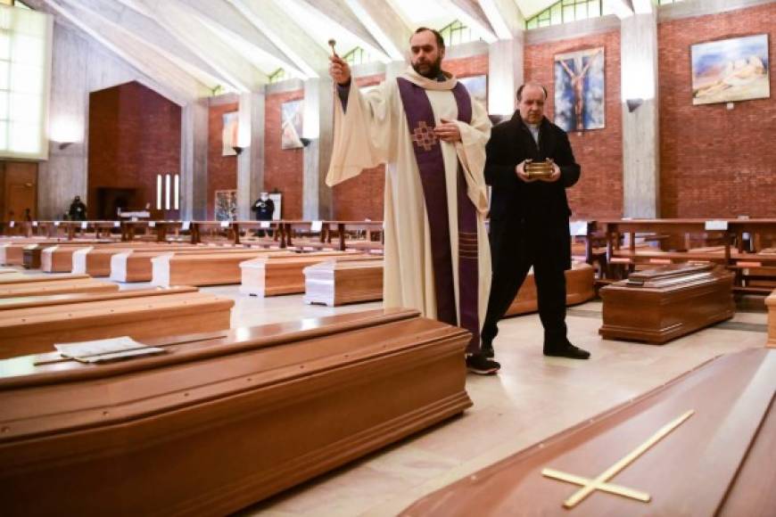 El sacerdote Don Marcello da una bendición a los ataúdes de las personas fallecidas dentro de la iglesia de San Giuseppe en Seriate en Italia.