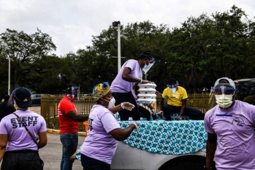In recognition of Easter, volunteers distribute food to people in need in the Little Haiti community at Notre Dame DHaiti Catholic Church, in Miami, Florida on April 11, 2020. - Drive-thru food distribution sites were set up across South Florida on April 11, 2020 as the financial grip of the coronavirus pandemic hits home. (Photo by CHANDAN KHANNA / AFP)
