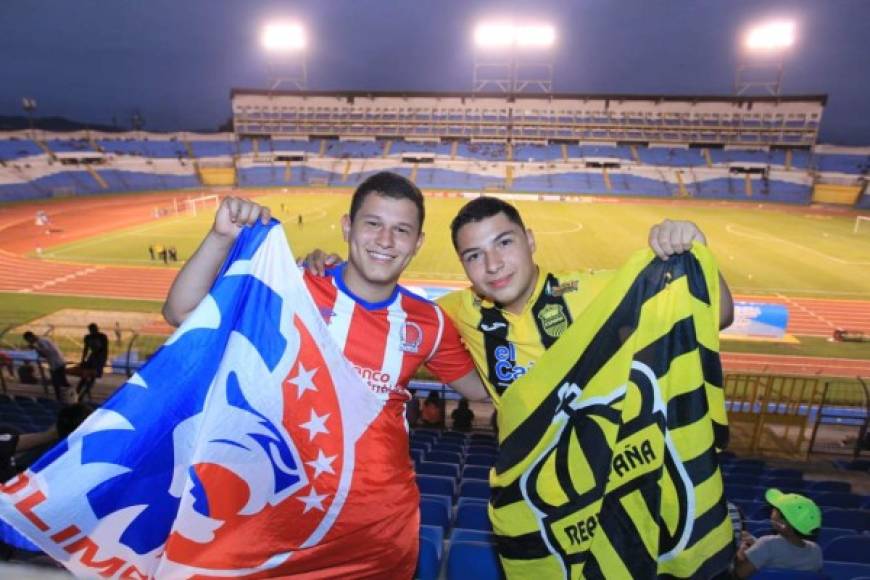 Dos aficionados, uno de Olimpia y otro del Real España, posando con las banderas de sus equipos antes del inicio del partido.