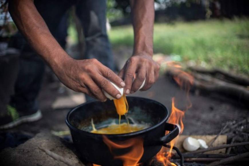 Otros migrantes cocinan sus alimentos en fuegos improvisados en las cercanías de las vías del tren.