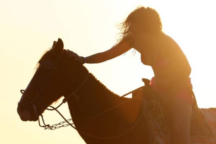 Un venezolana montando en un caballo en una puesta de sol en Puerto Cortés.