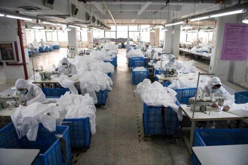 This photo taken on February 28, 2020, shows workers sewing hazardous material suits to be used in the COVID-19 coronavirus outbreak, at the Zhejiang Ugly Duck Industry garment factory in Wenzhou. - The coronavirus outbreak in China is preventing clothing manufacturer Ugly Duck Industry from resuming its normal production of winter coats, so it has pivoted to another in-demand product: hazmat suits. (Photo by NOEL CELIS / AFP) / TO GO WITH AFP STORY HEALTH-VIRUS-CHINA-HAZMAT-FACTORY,SCENE BY DAN MARTIN