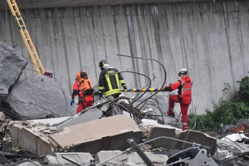 Miembros de los servicios de emergencia buscan sobrevivientes entre los escombros mientras esperan la llegada de maquinaria pesada para levantar los enormes bloques de concreto.