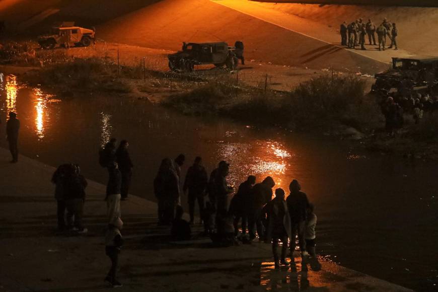 Migrants warm up around a campfire on the banks of the Rio Grande, where Texas National Guard agents prevent them from turning themselves in to Border Patrol agents in the El Paso Sector, after having crossed the Rio Bravo/Rio Grande from Ciudad Juarez, state of Chihuahua, Mexico. December 20, 2022. (Photo by HERIKA MARTINEZ / AFP)