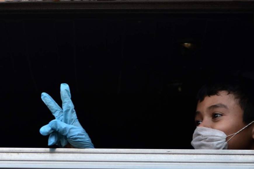 un niño migrante hondureño deportado de México, haciendo gestos desde la ventana del autobús, antes de ser puesto en cuarentena para evitar la propagación del coronavirus. AFP