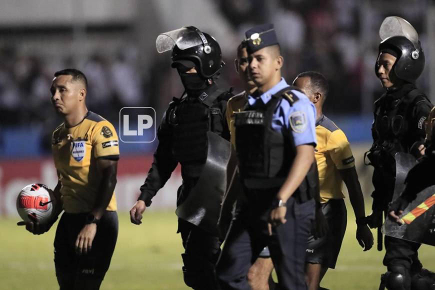 El árbtiro salvadoreño Iván Bartón y compañeros salen escoltados por la Policía Nacional tras el final del partido.