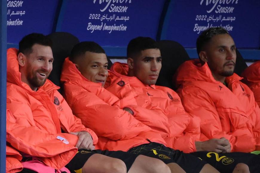 Messi y Mbappé sonriendo en el banco de suplentes tras salir de cambio.