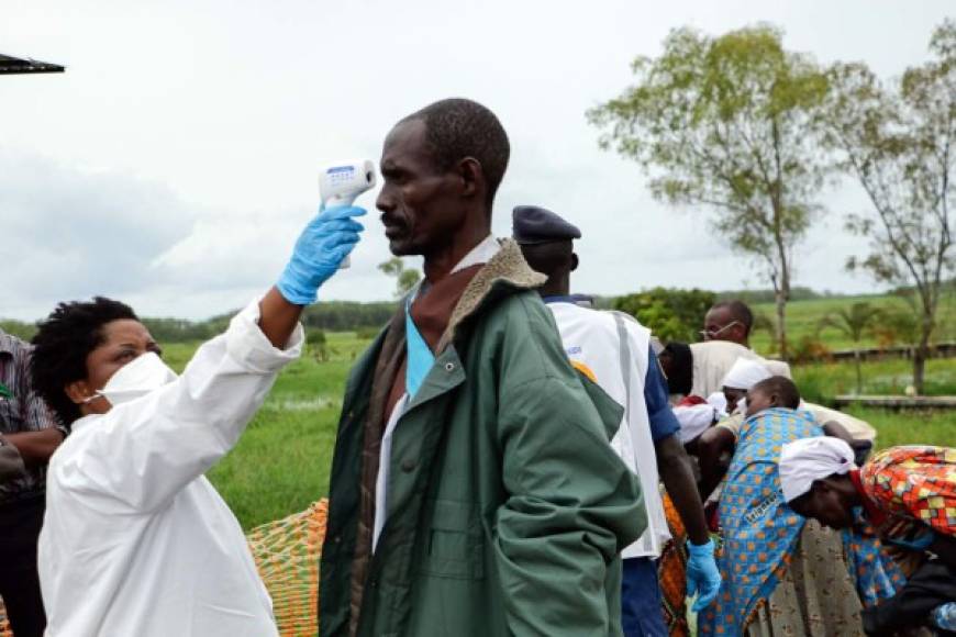 Un miembro del personal médico mide la temperatura de un hombre como medida preventiva contra el coronavirus COVID-19 a su llegada de repatriación a Gatumba, en la frontera con la República Democrática del Congo (RDC), en Burundi. Foto AFP