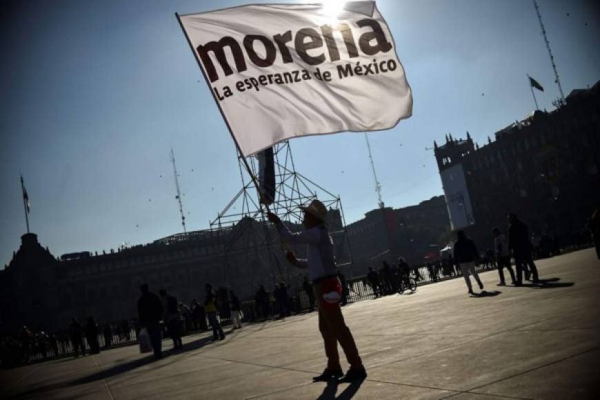 Un partidario del presidente electo de México, Andrés Manuel López Obrador ondea una bandera del partido antes del inicio de la ceremonia de inauguración, en la plaza del Zócalo, en la Ciudad de México.