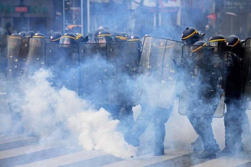 French CRS anti-riot police officers stand behind tear gas during a march for the annual May Day workers' rally in Paris on May 1, 2017. / AFP PHOTO / Christophe ARCHAMBAULT
