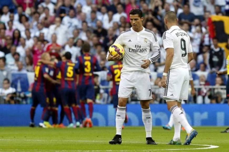Lo jugadores del Real Madrid, Cristiano Ronaldo y Karim Benzema, con el balon mientras los jugadores del Barcelona celebran el primer gol del partido.