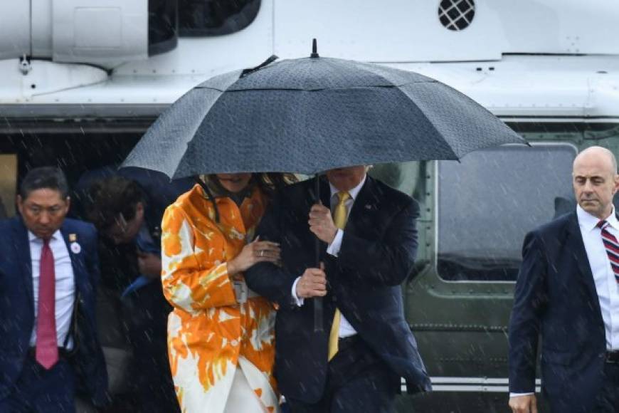 US President Donald Trump and First Lady Melania Trump use an umbrella as they arrive to board the Air Force One at Haneda international airport in Tokyo on May 28, 2019. (Photo by Brendan SMIALOWSKI / AFP)
