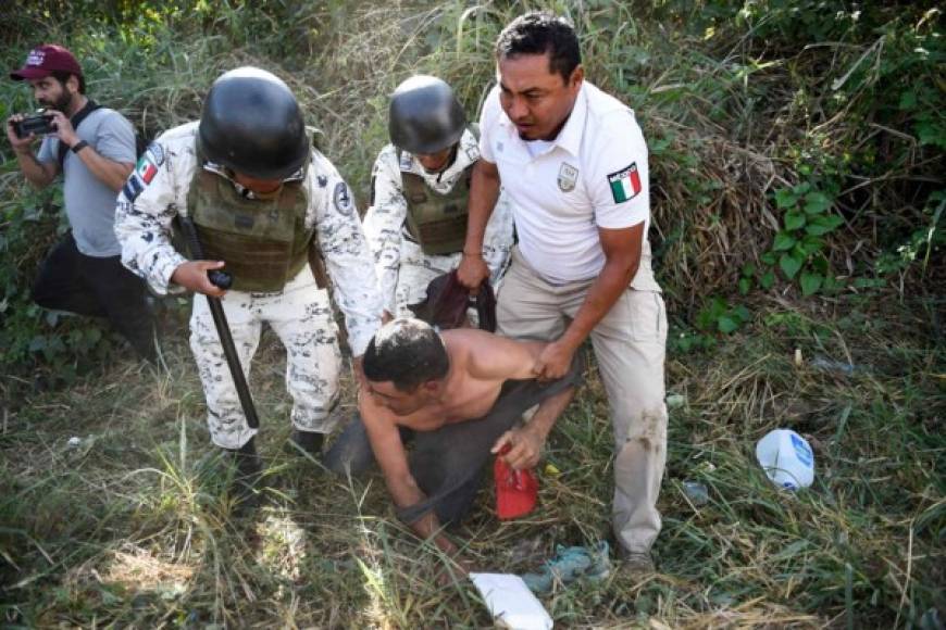 Members of the Mexican National Guard and officers of the Migration Institute detain a Central American migrant - heading in a caravan to the US - in Ciudad Hidalgo, Chiapas State, Mexico, on January 23, 2020. - Hundreds of Central American migrants surged into Mexico Thursday, wading unopposed across a river on the Guatemalan border where Mexican troops had used tear gas earlier in the week to keep them back, AFP journalists at the scene reported. (Photo by ALFREDO ESTRELLA / AFP)