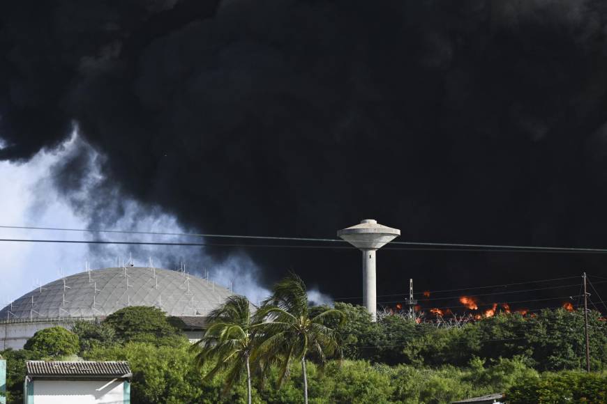 Black smoke from an oil tank on fire is seen in Matanzas, Cuba, on August 6, 2022. - The fire caused by lightning on Friday in a fuel depot in Matanzas, in western Cuba, spread to a second tank at dawn this Saturday and caused 49 injuries, official sources reported. (Photo by YAMIL LAGE / AFP)
