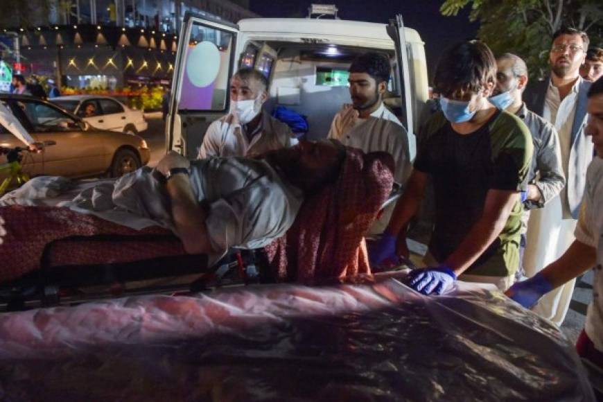 EDITORS NOTE: Graphic content / Volunteers and medical staff bring an injured man for treatment after two powerful explosions, which killed at least six people, outside the airport in Kabul on August 26, 2021. (Photo by Wakil KOHSAR / AFP)