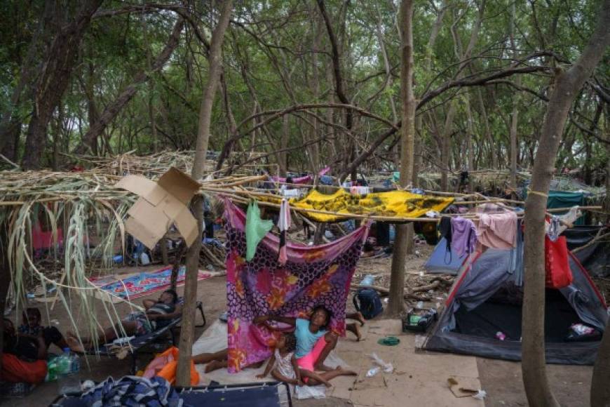 Los migrantes han improvisado tiendas de campaña con trozos de tela para resguardarse del sol brutal, utilizan botellas de agua para bañarse y están rodeados de basura acumulada.